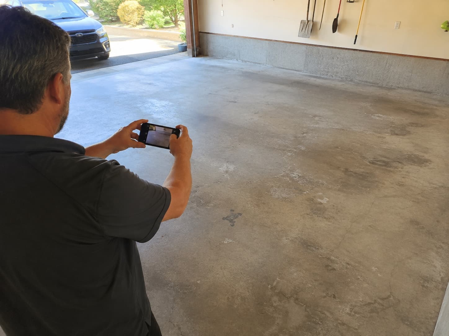Homeowner photographing his bare garage floor with his phone